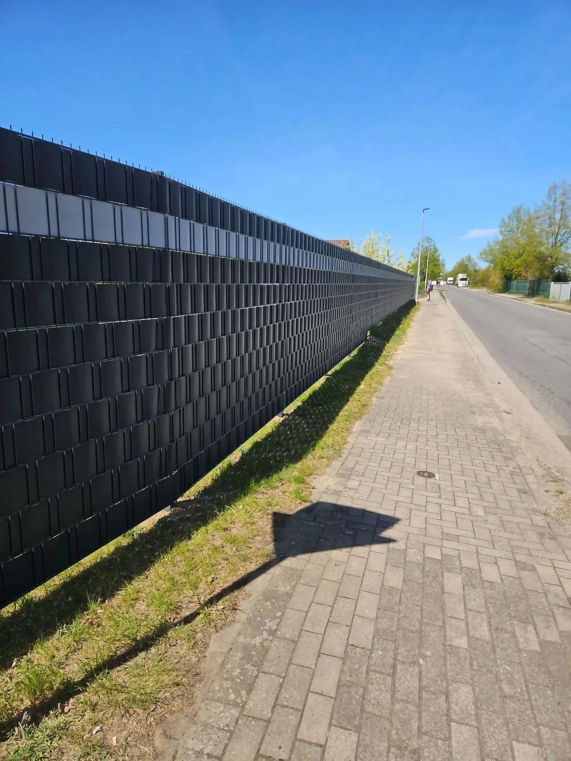 Langer Doppelstabmattenzaun in Anthrazit mit Sichtschutzstreifen entlang der Straße als Grundstücksgrenze