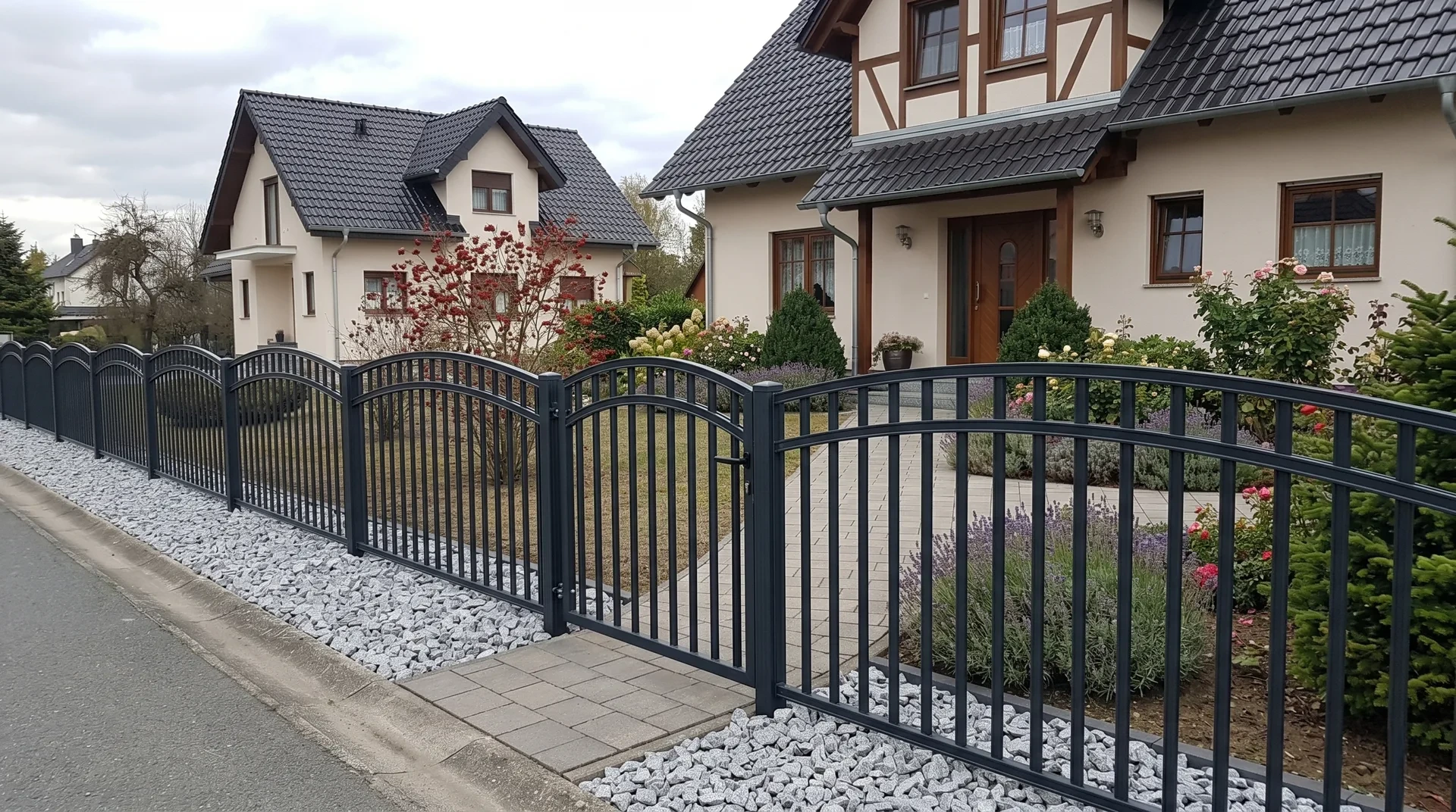 Schmiedezaun in Anthrazit mit Bogenelementen und Kiesbeet vor Fachwerkhäusern in Rostock